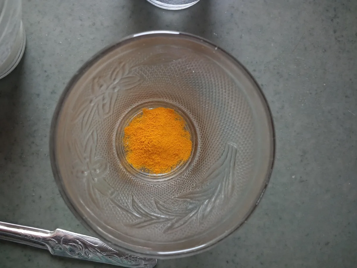 Racines de curcuma, poudre orange et petit bol d'huile sur une table de cuisine