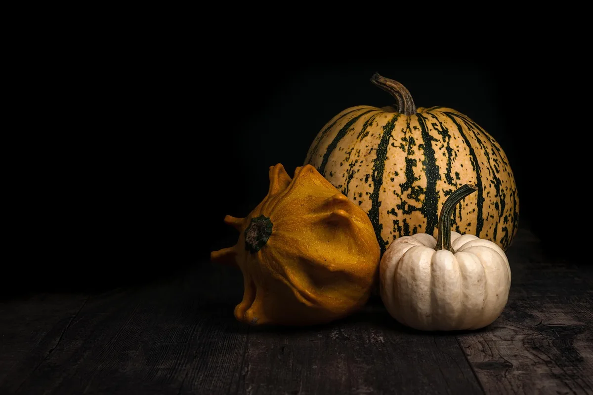 Bol de graines de courge décortiquées et graines entières sur une table en bois