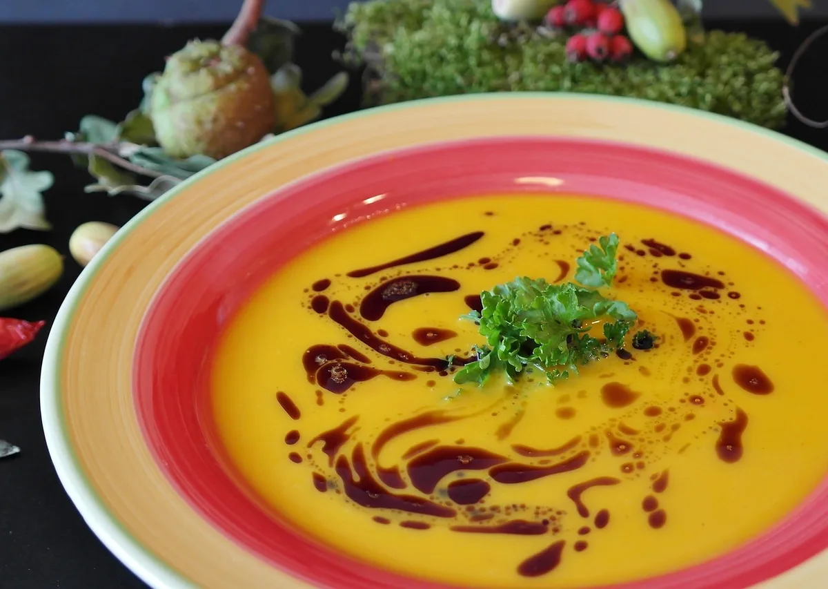 Bol de graines de courge non identifiables versé sur une salade, main anonyme en action