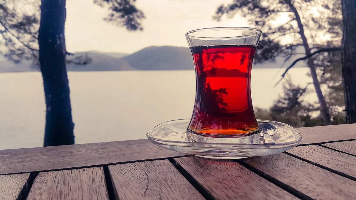 Personne anonyme feuilletant des fiches mémoire sur une table avec lunettes et tasse de thé