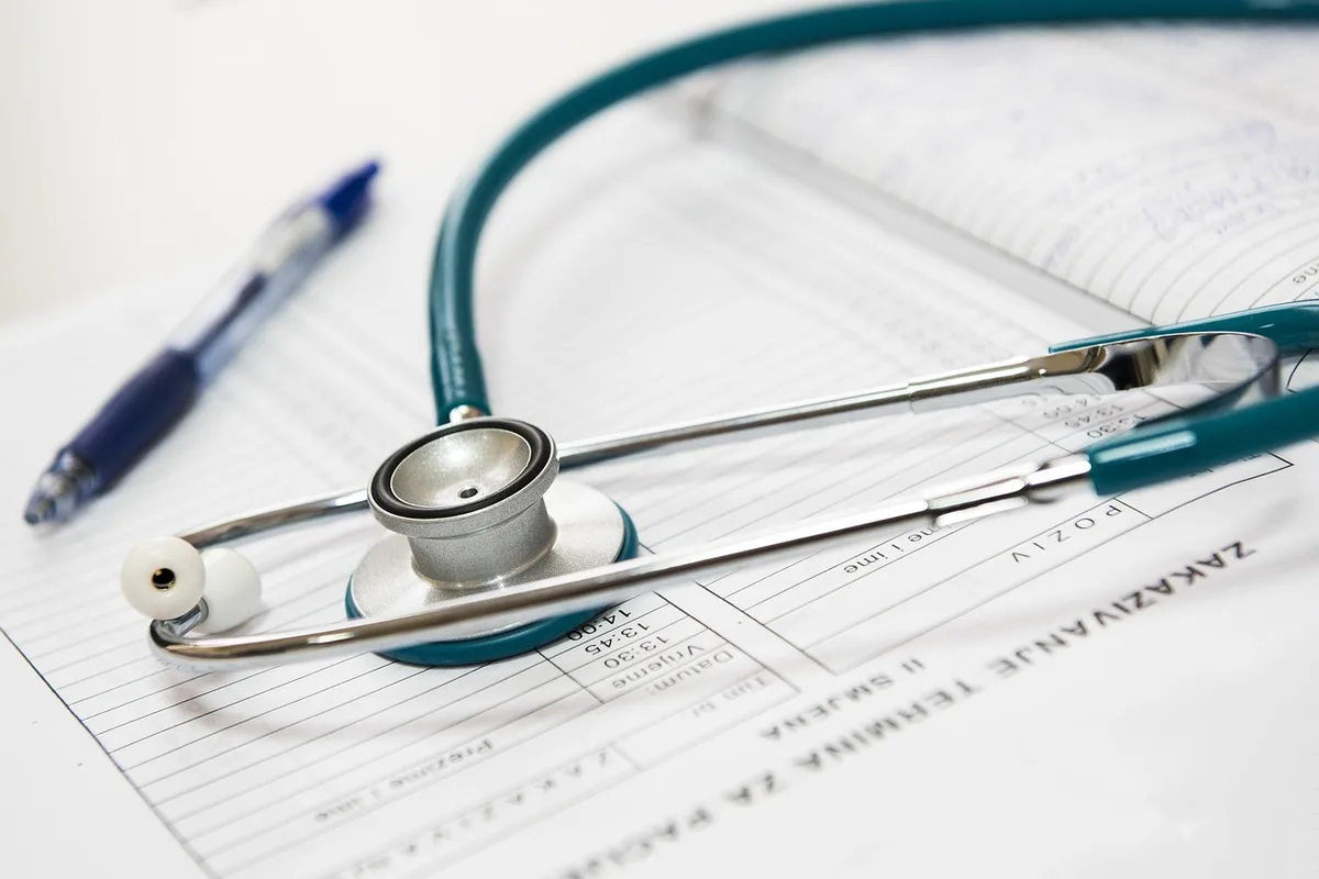 Mains anonymes près d'un tensiomètre et d'un stéthoscope sur une table de consultation