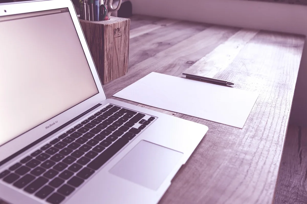 Petits appareils auditifs rechargeables posés sur une table, mains en arrière-plan
