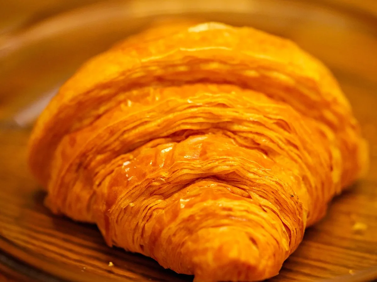 Assiette de viennoiseries nature sur une table de petit-déjeuner, lumière du matin